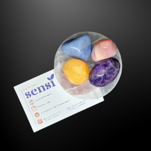 Een roze agaat abrikoos, paarse amethist, blauw kwarts en oranje calciet. Deze vier edelstenen liggen op een ronde witte seleniet oplaadsteen.