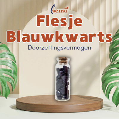 Een glazen wensbuisje met daarin stukjes blauwkwarts. Hij staat op een houten ronde schijf en er zijn planten op de achtergrond.